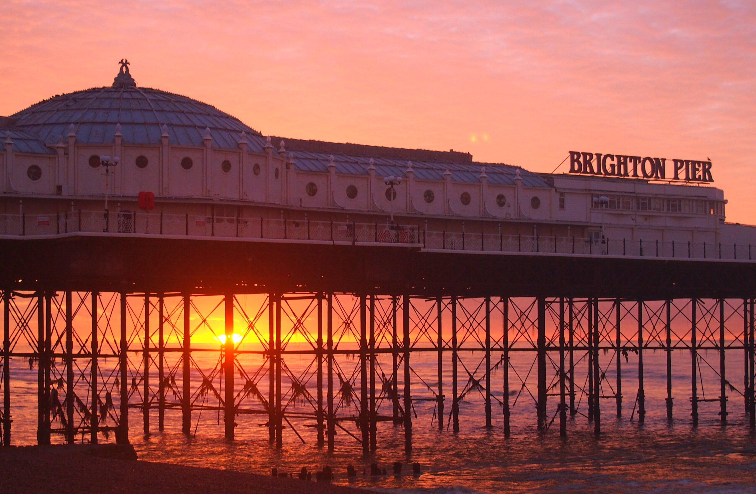 Brighton Palace Pier at sunrise with the sun beneath the deck