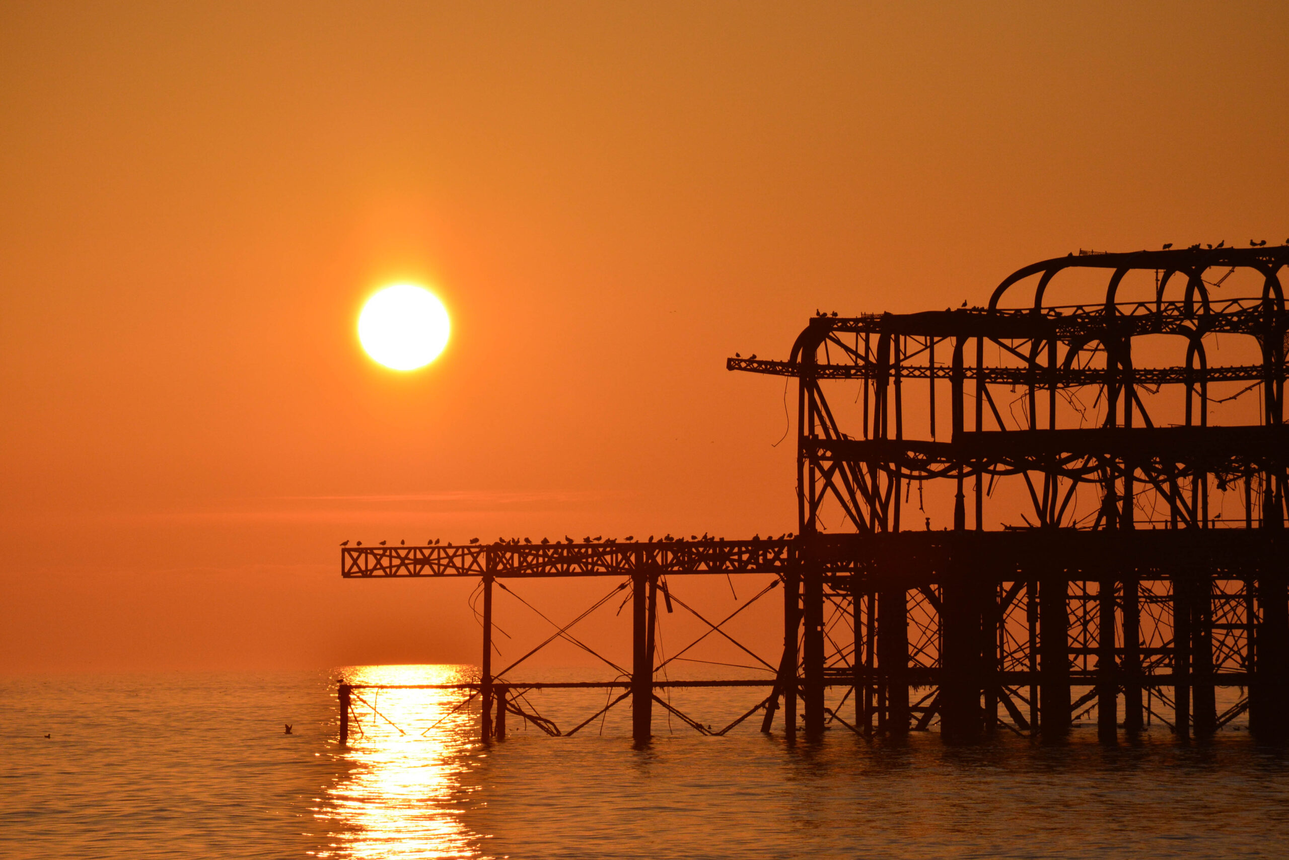 The West Pier silhouetted against an orange sunset
